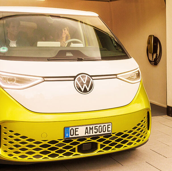 Familie fährt mit gelben E-Auto aus der Garage, daneben hängt eine AMTRON 4You 500 Wallbox in gelb.