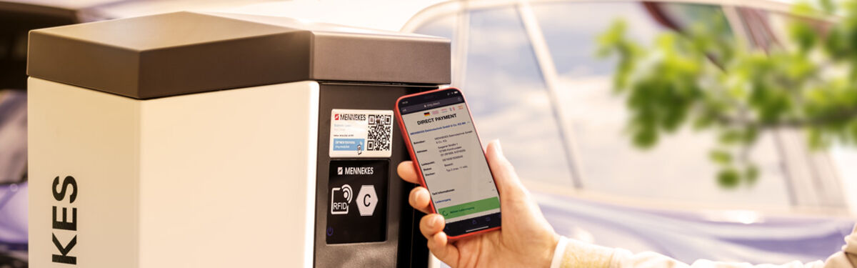 Person scannt an einer Ladesäule den QR-Code mit dem Smartphone